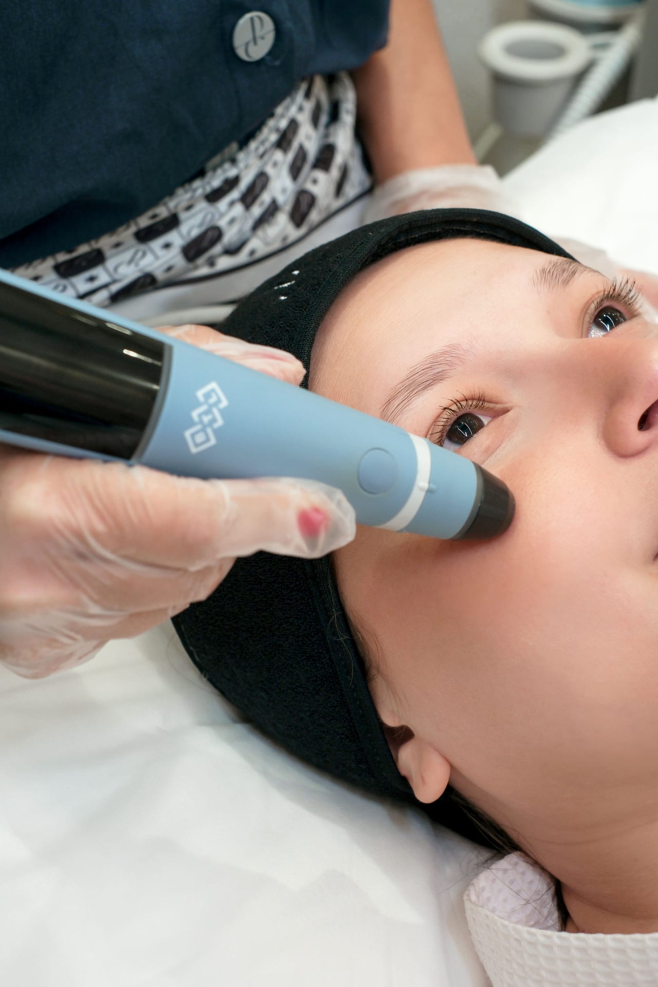 Profissional realiza procedimento facial com dispositivo dermatológico na região dos olhos