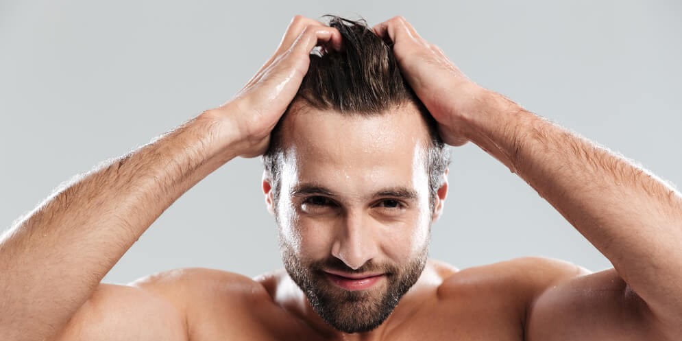 Homem com boa aparência pegando nos cabelos após tratamentos capilares masculinos